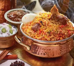 A fragrant mutton biryani fills a gleaming copper bowl to the brim, bursting with savory goodness.