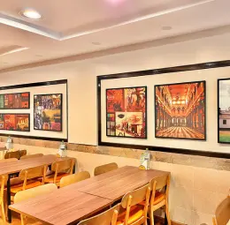Tables and chairs are arranged on the restaurant terrace, and decorative pictures cover the wall.