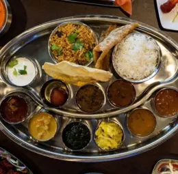 Indian Veg Catering prepares a diverse assortment of food on a metal tray, showcasing various dishes
